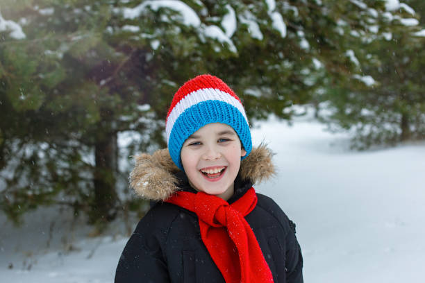 istock Happy boy in bright winter clothes and a red scarf walks during a snowfall 2157156027