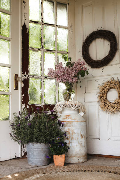 A fresh bouquet of lilacs, a pot of lavender, and wreaths set on a cozy, rustic porch.