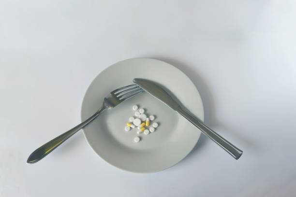 istock Colorful capsules and pills on plate with fork and knife on white background 2157157767