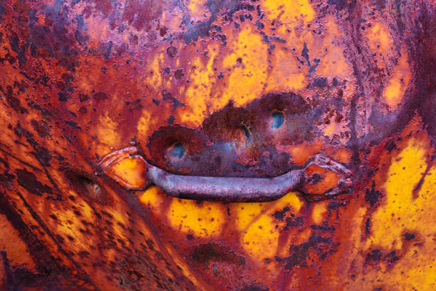 Rusty and Scratched Old Metal Sign with Bullet Holes - Orange, yellow and brown sign made of thick steel left outdoors to weather in the elements. Old equipment left abandoned. Details showing rust, scratches, dents, dings and bullet holes.