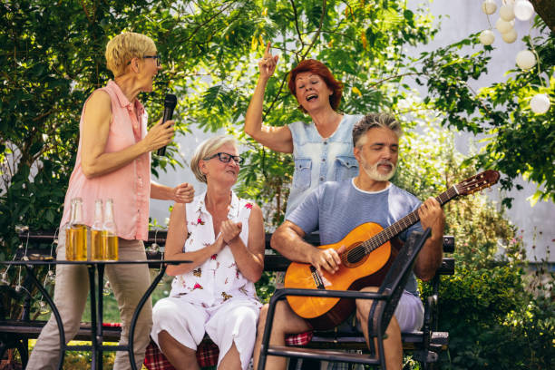 istock Group of elderly people enjoying their retirement by going on a picnic, playing a guitar and singing. 2157165232