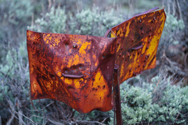 Rusty and Scratched Old Metal Sign with Bullet Holes - Orange, yellow and brown sign made of thick steel left outdoors to weather in the elements. Old equipment left abandoned. Details showing rust, scratches, dents, dings and bullet holes.
