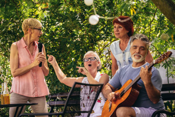 Group of elderly people enjoying their retirement by going on a picnic, playing a guitar and singing, making barbeque, making memories and making their friendship stronger