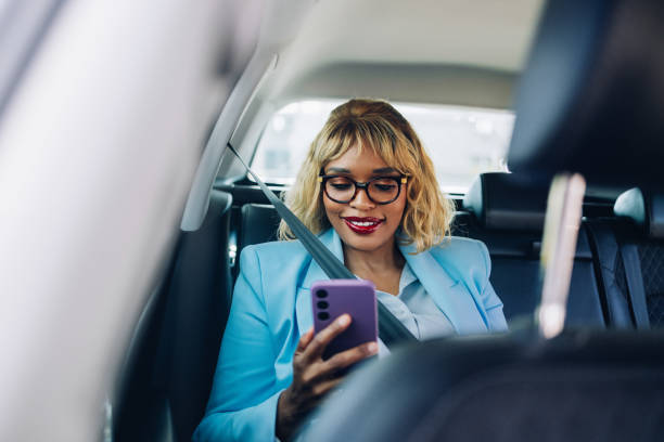 istock Businesswoman Using Smartphone in Car Wearing a Blue Blazer 2157165881