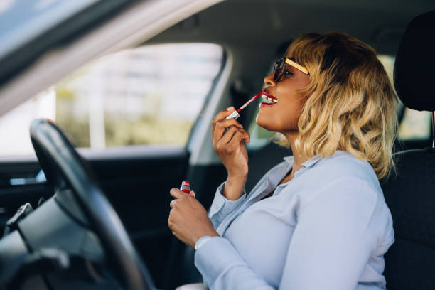 istock Woman Applying Lipstick in Car While Sitting in Driver's Seat 2157165906