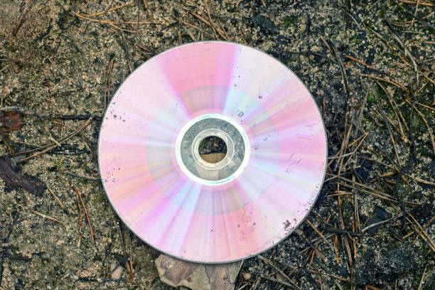 one old dirty colored compact disc lies on the gray ground in the street