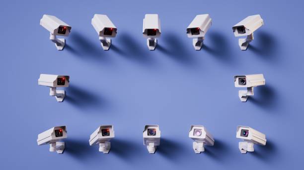 istock 3d render. White security cameras pointing to the blank spot in the center, isolated on blue background. Metaphor of total control. Concept of security monitoring 2157168150