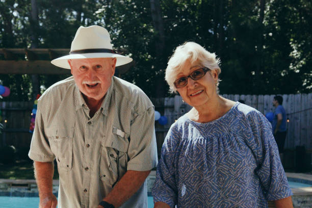 A senior aged Hispanic couple preparing food for a backyard summer party.