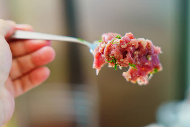 Fork lifting fresh ground meat with herbs, prepping for a flavorful meal