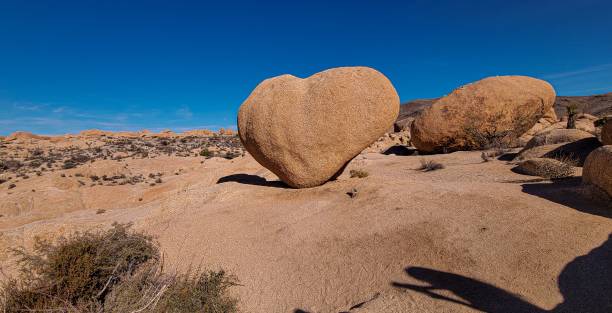 A heart-shaped rock formation in Joshua Tree National Park under a clear blue sky.
