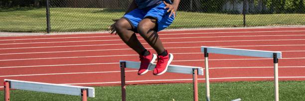 istock Athlete jumping over hurdles on a turf field at practice 2157178678