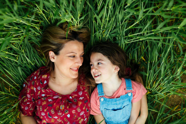 istock Mother and daughter having a bonding time lying in a wheat green field 2157179247