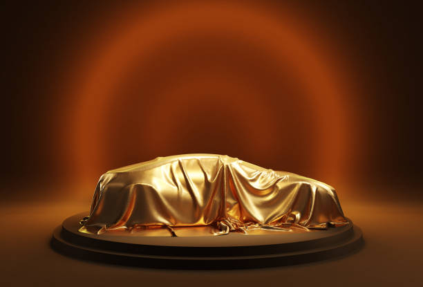 istock Car covered with golden cloth on a dark background. 2157181263