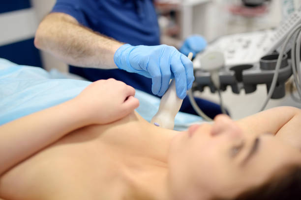 mammologist doctor examines a woman breasts and lymph nodes using ultrasound. mammography and ultrasound scanning are main methods of instrumental diagnosis of mammary glands. breast cancer - boobs stockfoto's en -beelden
