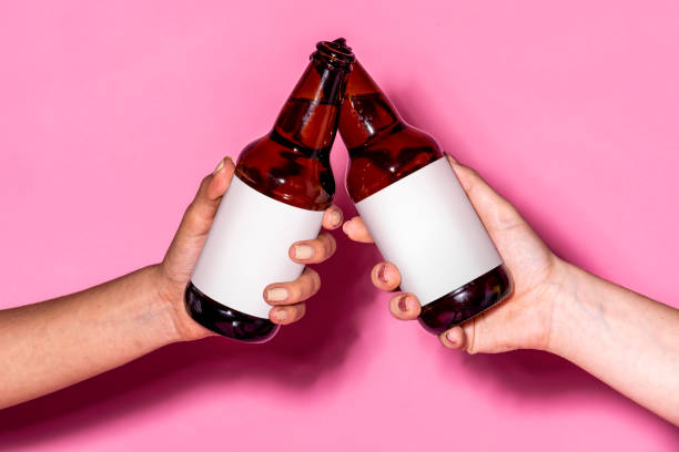 istock Hands holding beer bottles against a pink background 2157192290