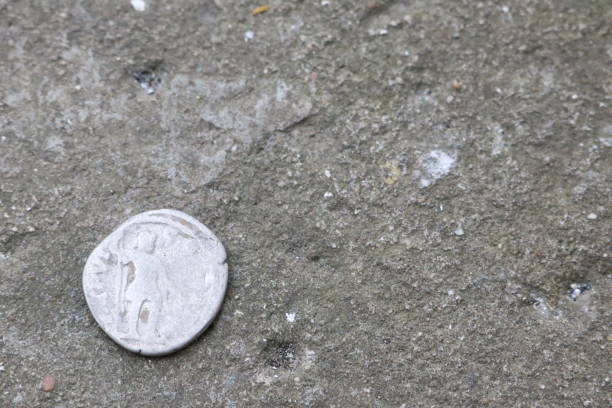 istock A historic silver coin is placed on a coarse concrete surface, showcasing its antiquity and value 2157192758