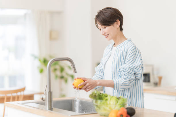 istock A woman is washing vegetables in the kitchen. 2157195304