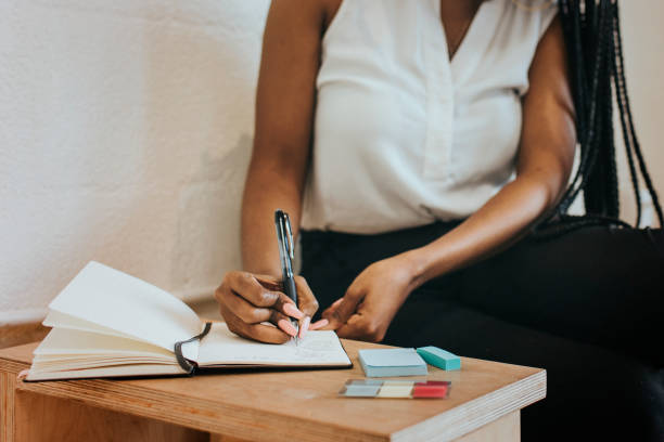 istock Black woman writing on a notebook in a cafe 2157195613