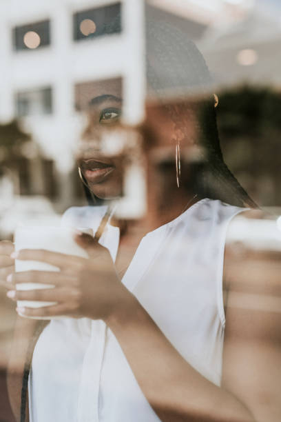 istock Woman enjoying a cup of coffee while looking out the window 2157195651
