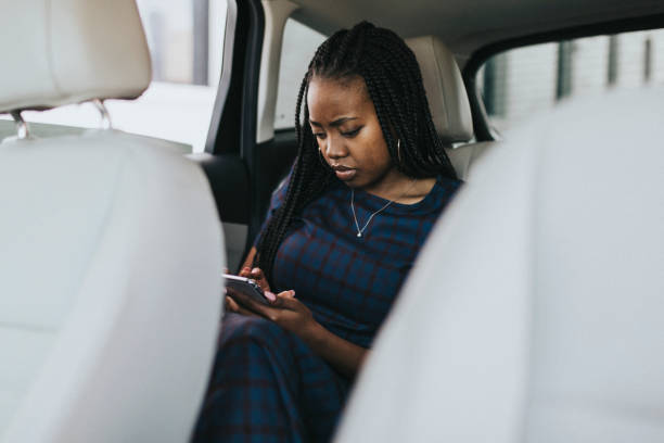 istock Black woman sitting in the passenger seat using her phone 2157195864