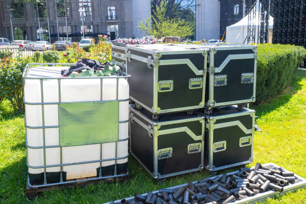 istock Protective boxes for concert equipment. Barrel liquid on lawn. Equipment for creating construction concert venue. Boxes with musical apparatus and summer sky. Tubes for construction concert structure 2157200103