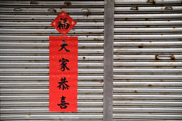 TWN-05.25.24: During Chinese New Year, door couplets are posted using red paper and calligraphy brushes to write blessings, symbolizing auspiciousness and prosperity, a quintessential cultural symbol.