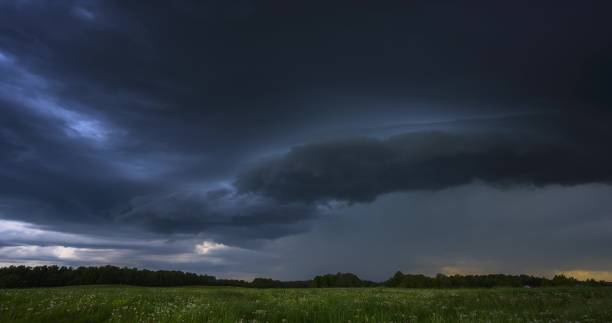 istock A stormy sky hangs over a grassy field with trees in the backdrop 2157222638