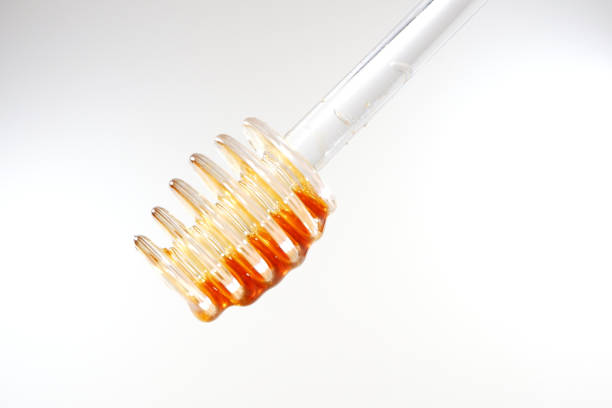 Transparent honey dipper isolated on white background close-up view