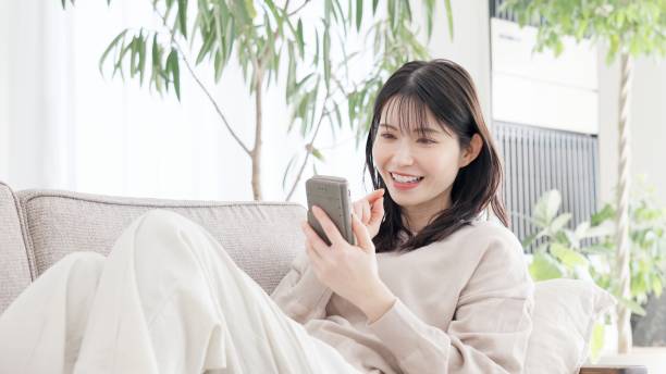 istock A woman relaxing on a sofa and looking at her smartphone 2157225652