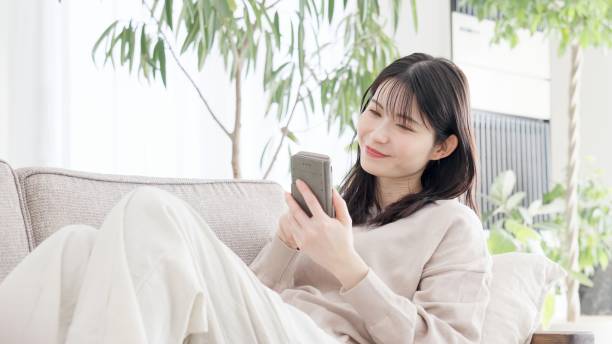 istock A woman relaxing on a sofa and looking at her smartphone 2157225657