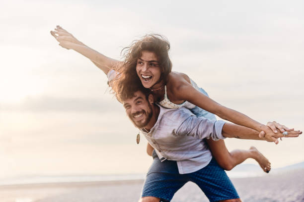 istock Cheerful couple piggybacking on the beach. 2157230450
