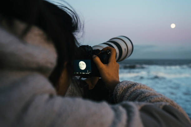 Photographer capturing the Moon by the sea