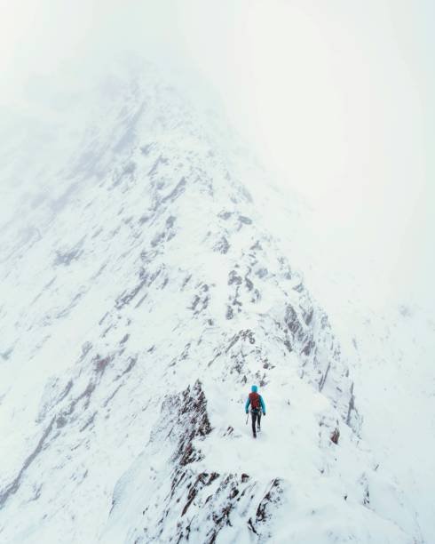 Mountaineer using an ice axe to climb Forcan Ridge in Glen Shiel, Scotland