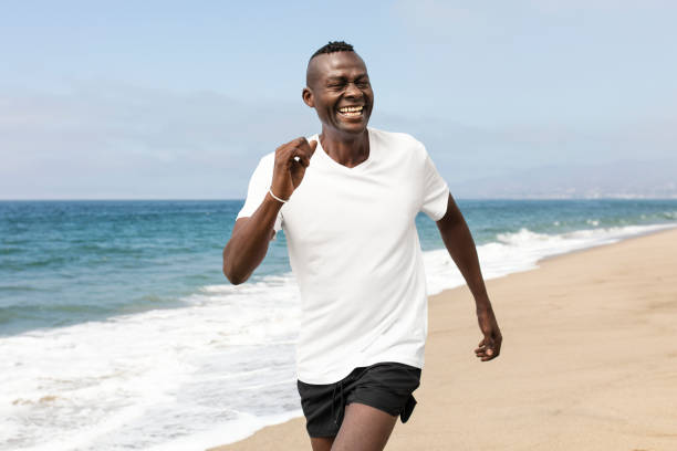 Two women jog along the pebbled beach of Lake Baikal under a bright blue sky on a sunny day. Running girls. Young women runner jogging on the beach. Teenagers training outdoors. Exercising  on the beach. Healthy, fitness, wellness lifestyle. Sport, cardio, workout concept