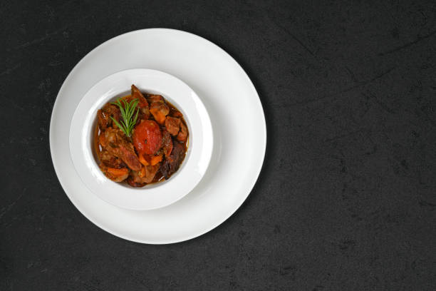 Top view of main course, roast veal with sauce, dumplings, leeks and carrots served on a plate.