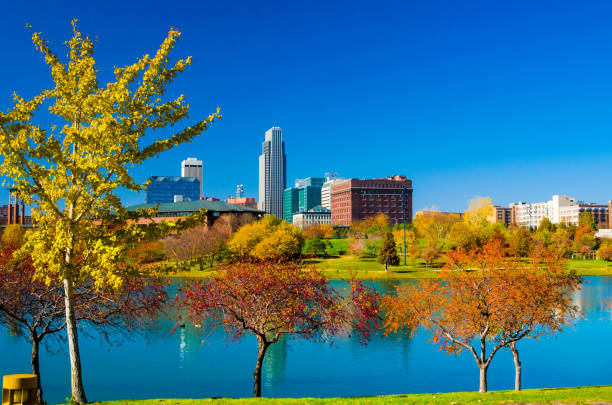 Downtown Omaha skyline with a park, lake, and various autumn colored trees.