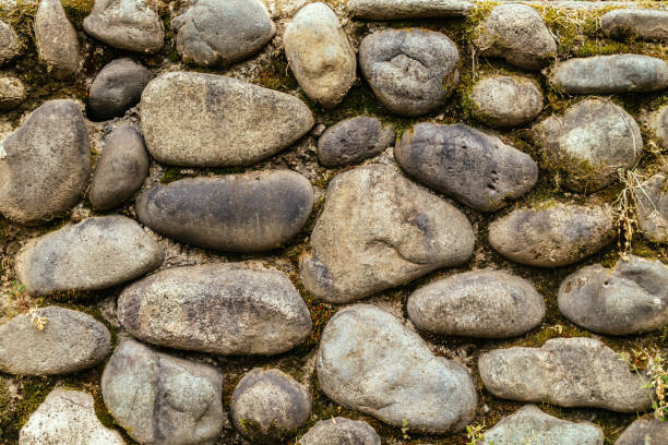 Old stone wall made of grey pebbles, background