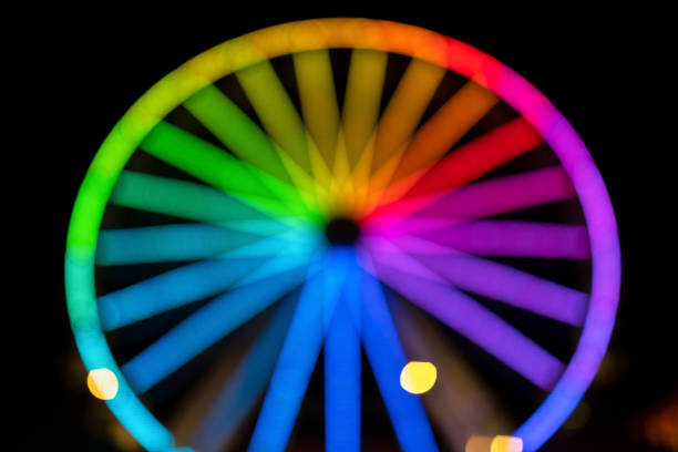Blurry image of ferris wheel at night festival with bokeh background. Abstract blurry photo of game rides in night festival city park bokeh background with colorful lights at night.