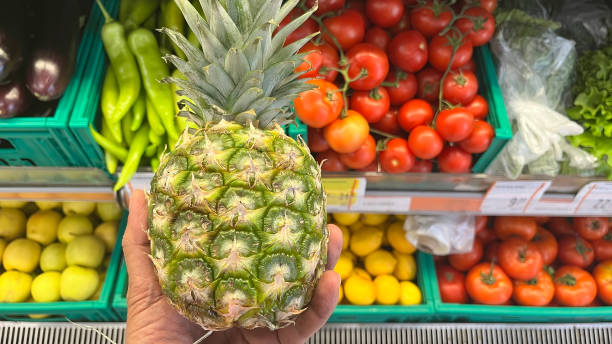 istock A man holding a pineapple at a market stall. 2157239108