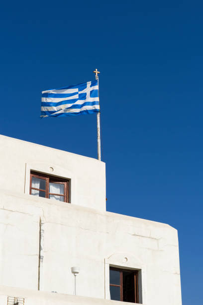 Greek flag on the building in a blue summer sky. Copy space. Vertical image.