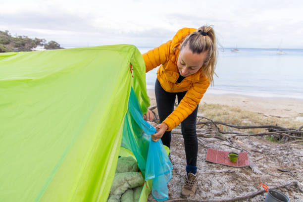 istock Woman Setting Up Tent by the Beach 2157241695