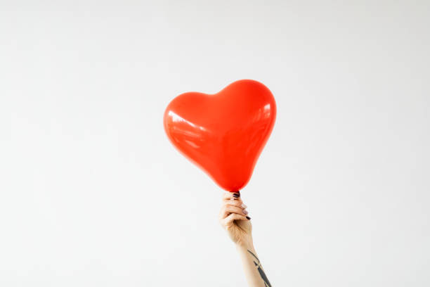 istock Tattooed arm holding a red heart shape balloon 2157244878