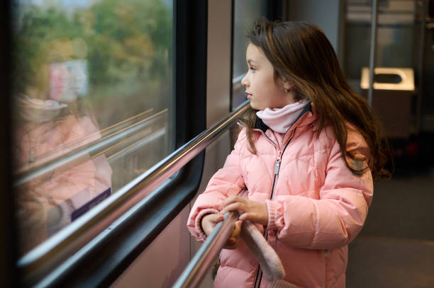 istock Little girl in pink jacket looking out window on a train ride 2157248408