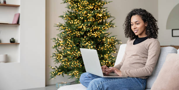 istock Woman  using laptop computer at home with Christmas tree at background 2157250625