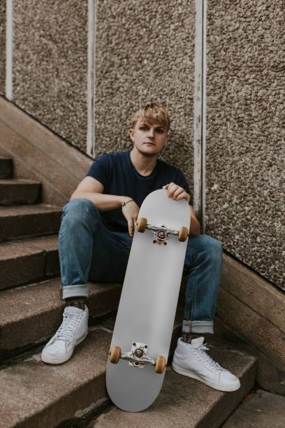 istock Cool man with gray skateboard sitting on steps 2157251370