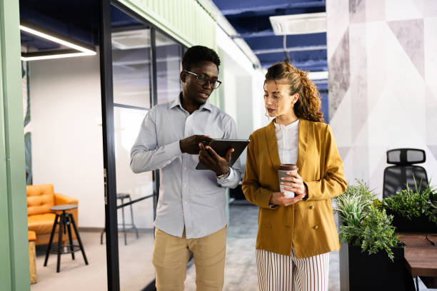 istock Multiracial female and male coworkers, analyzing a business plan on a digital tablet, while walking through the office 2157251521