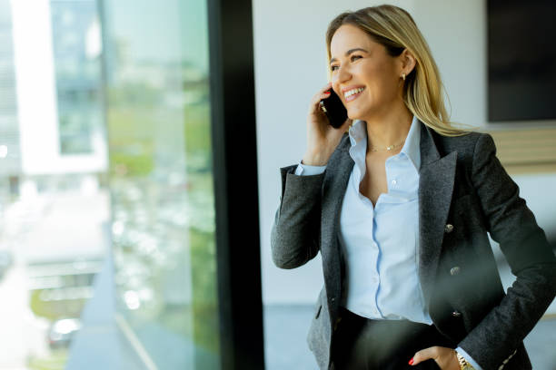 istock Young professional woman talking on mobile phone by office window on a sunny day 2157252464