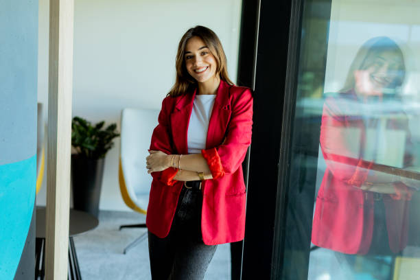 istock Confident young professional in red blazer smiling at modern office environment 2157254228
