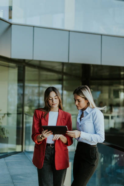istock Two business women collaborating outdoors with digital tablets on a sunny afternoon 2157254371