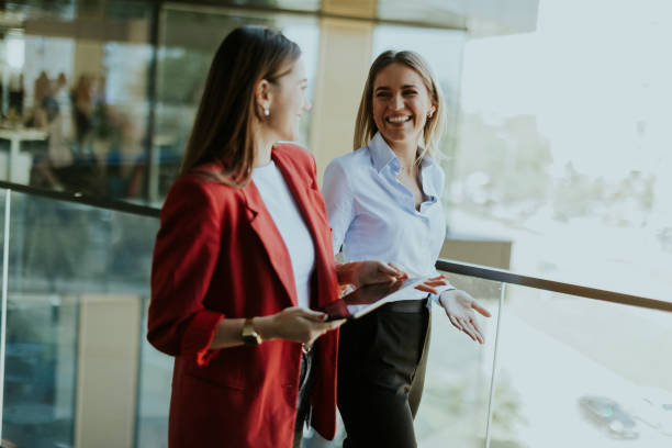 istock Two businesswomen discuss strategy outside modern office building in daylight 2157254377